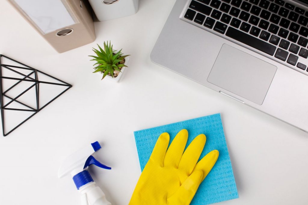 A person disinfecting an office desk