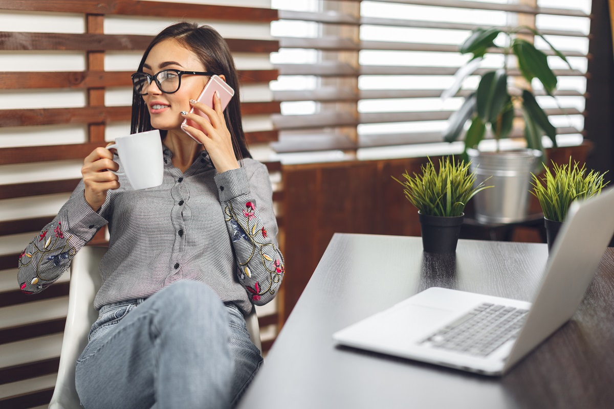 Happy smiling woman working with laptop and drinking coffee