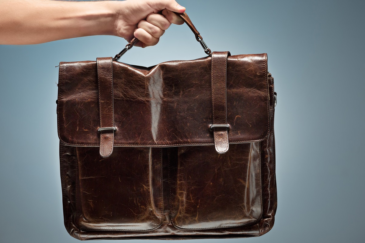 A man holding a brown leather travel bag